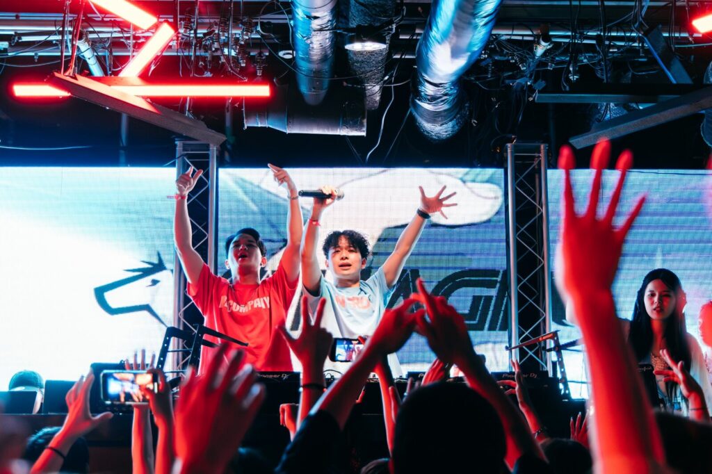明るいステージでDJに手を上げる観客